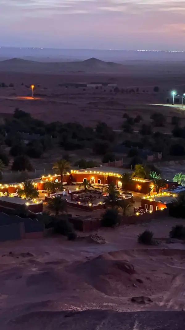Campement illuminé dans l'oasis à la tombée de la nuit